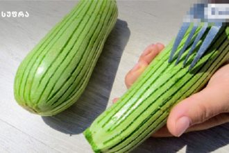 Close-up of a bright green striped rolled cake being cut with a fork to reveal the inside.